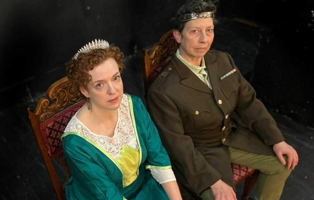 image of woman in green gown & tiara (Lady Macbeth) and man in uniform & crown (Macbeth) seated on thrones